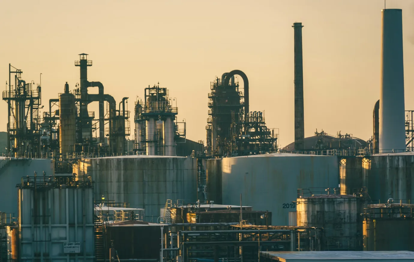 Industrial storage tanks, process towers and piping in warm evening light