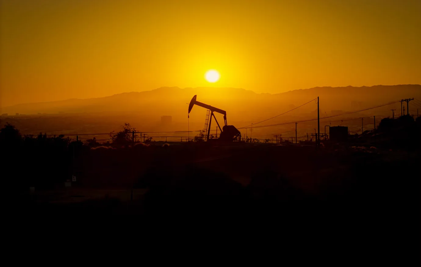 Oilfield pumpjack silhouetted against the setting sun